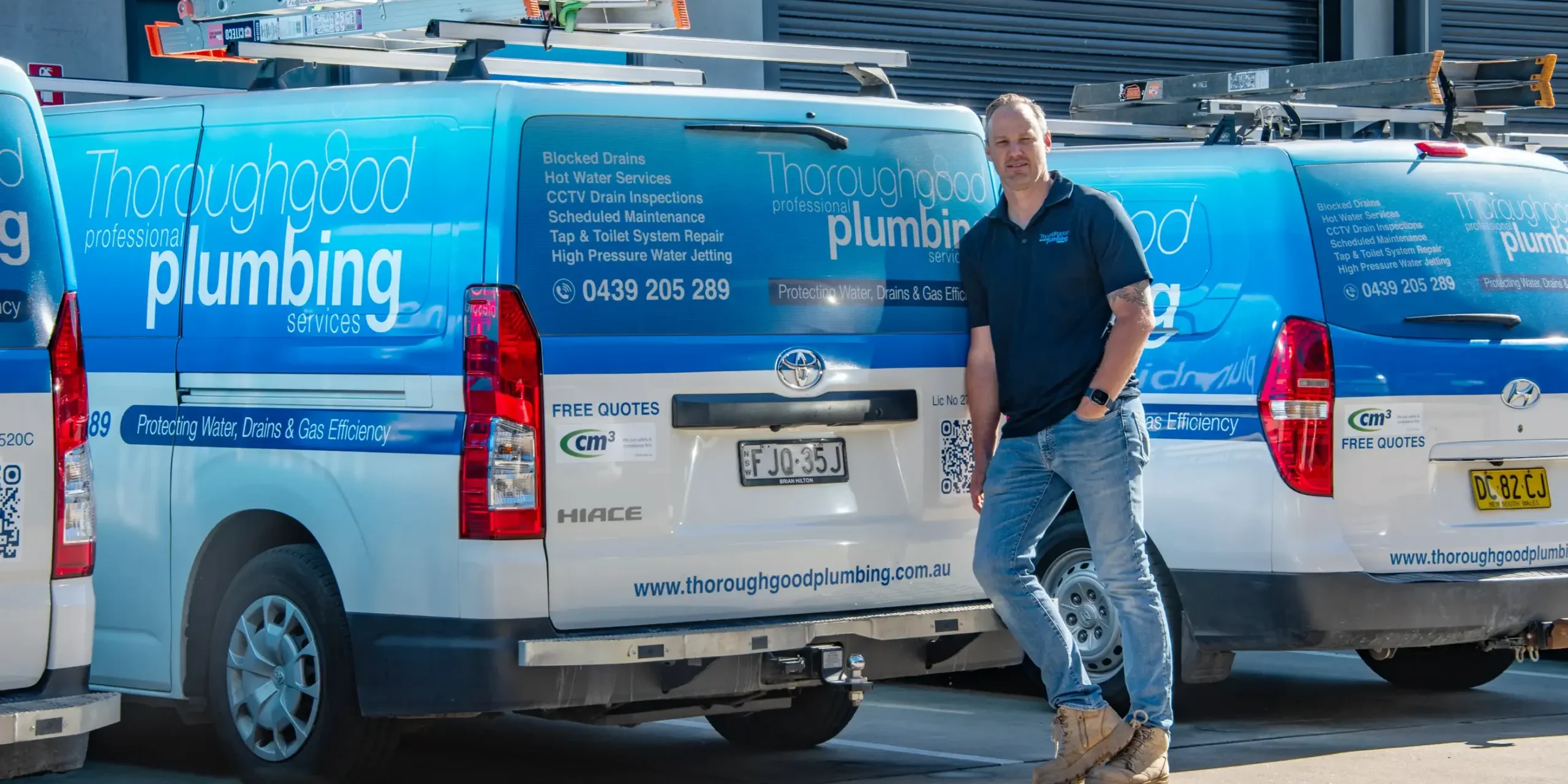 Thoroughgood Professional Plumbing Services owner standing in front of branded Toyota HiAce fleet vans, Central Coast NSW