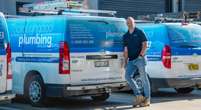Thoroughgood Professional Plumbing Services owner standing in front of branded Toyota HiAce fleet vans, Central Coast NSW